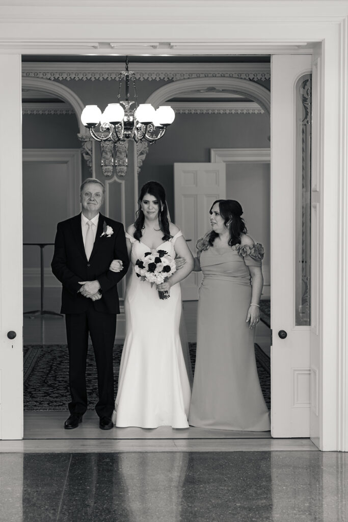 Bride and father poised at the doorway, anticipation etched on their faces, ready to walk down the aisle.