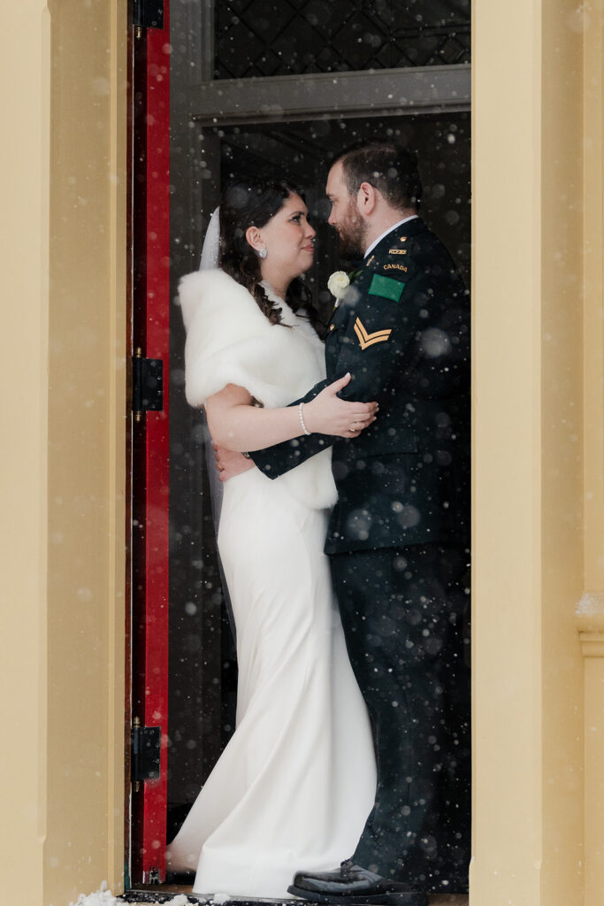 Bride and groom embrace outside in a snowy scene, capturing the essence of a winter wedding.