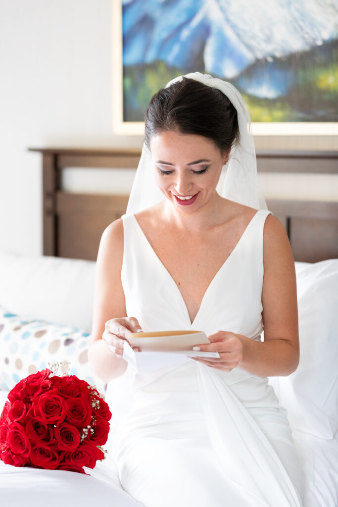 bride reading letter from the groom on her wedding day. She smiles while reading it